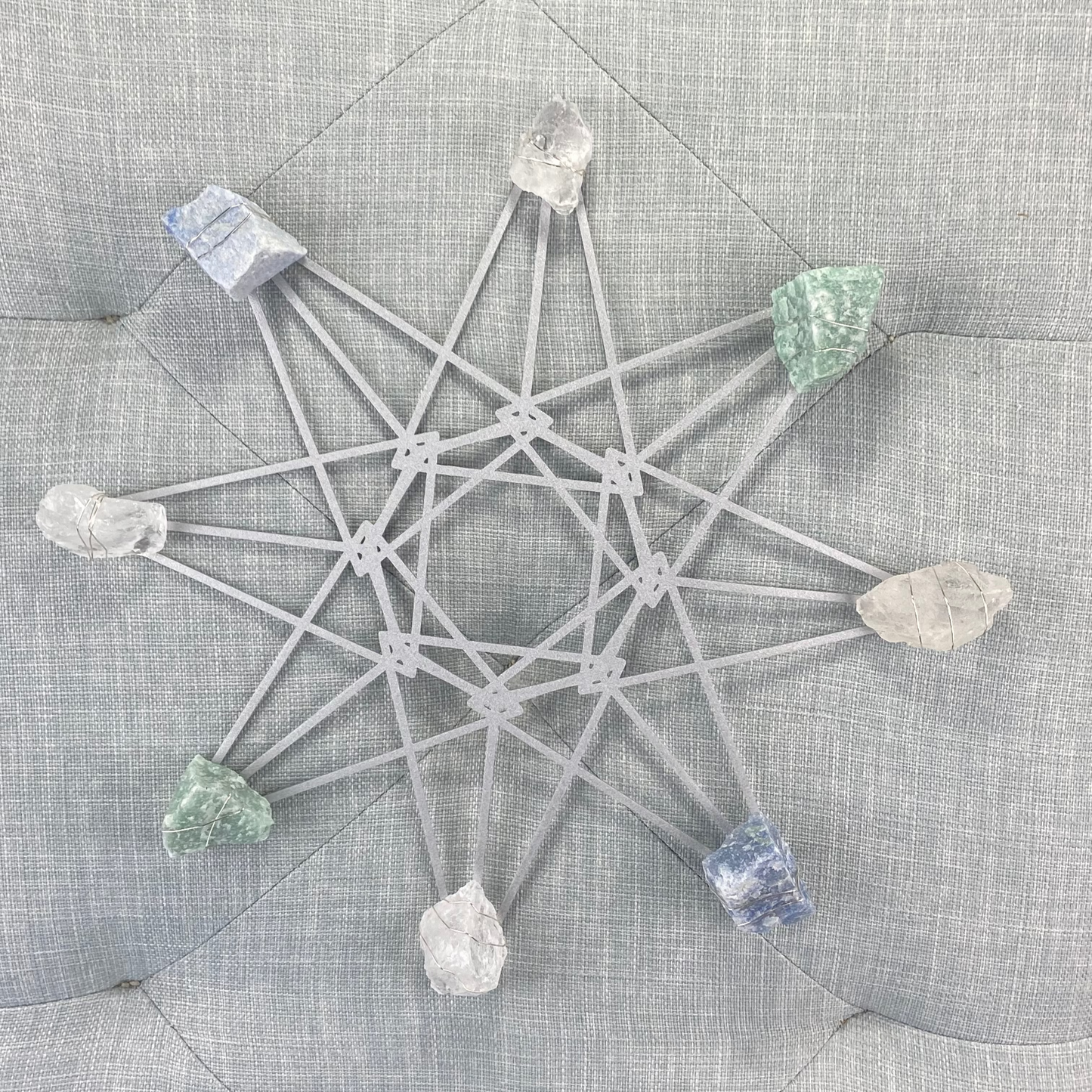Crystal grid with stones on a textured gray surface