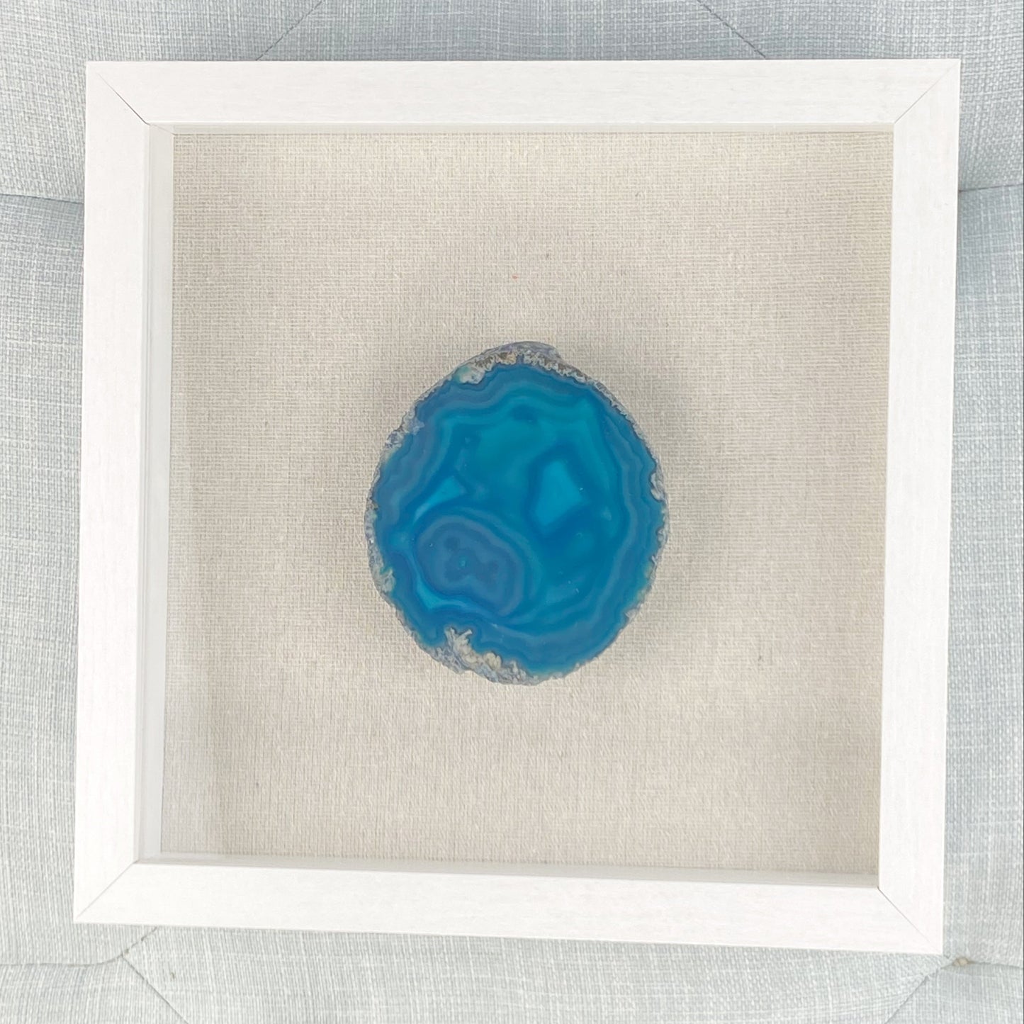 Blue agate stone in a white frame on a textured gray background