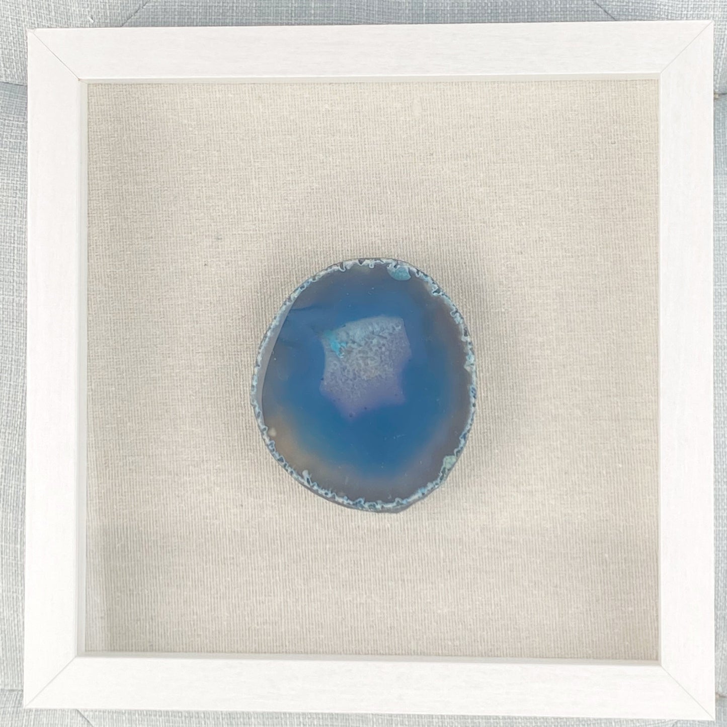 Blue agate stone in a white frame on a light gray background