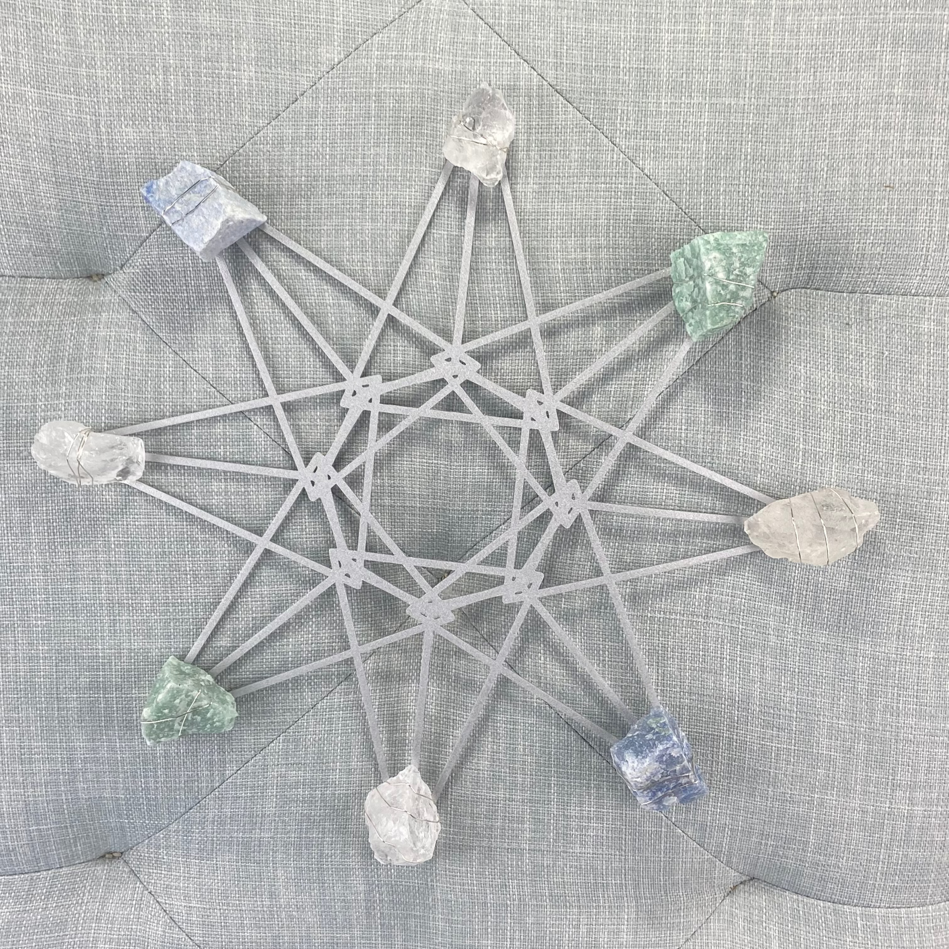 Crystal grid with stones on a textured gray surface