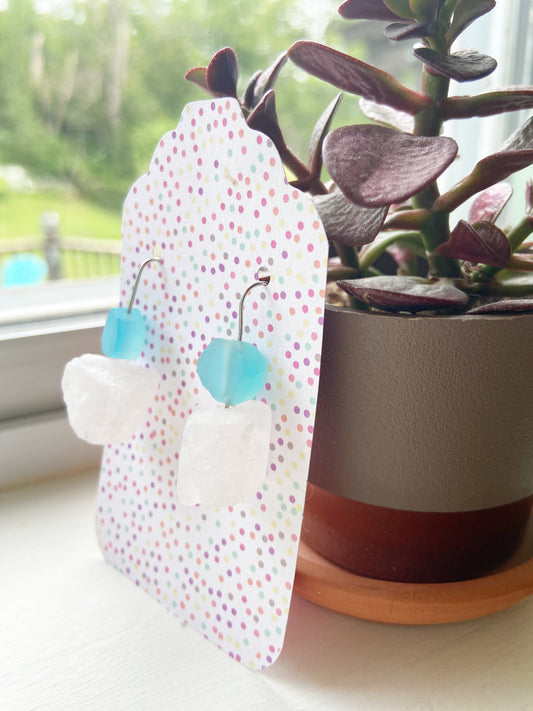 Polka dot earring holder with blue earrings next to a potted plant