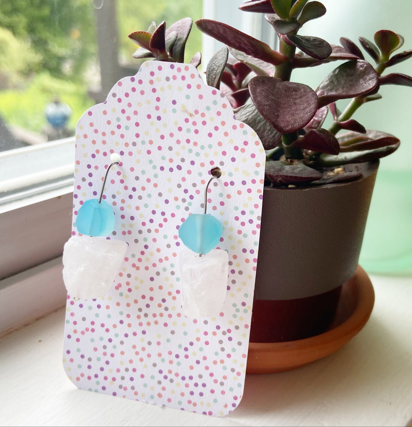 Small potted plant on a windowsill with a decorative tag
