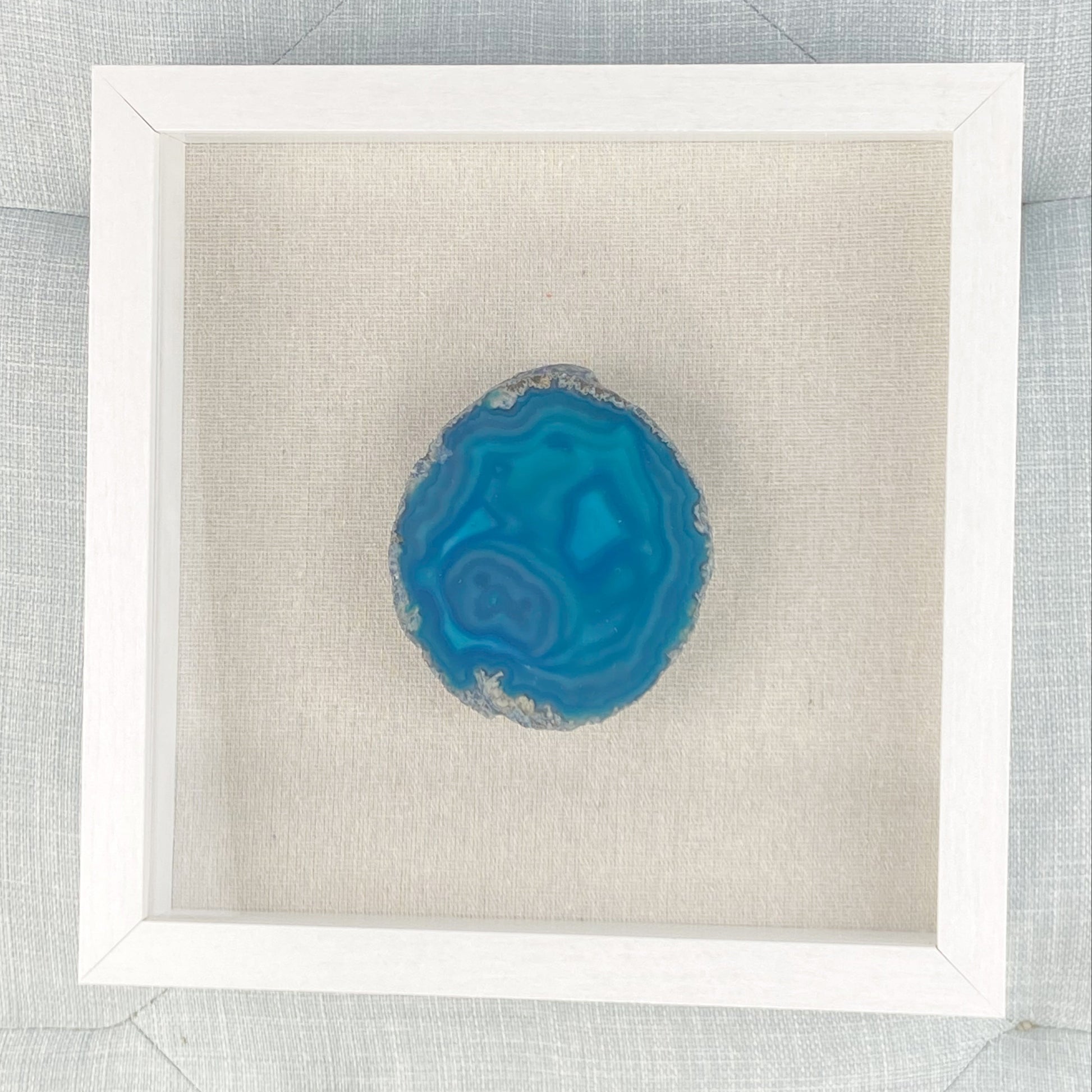 Blue agate stone in a white frame on a textured gray background