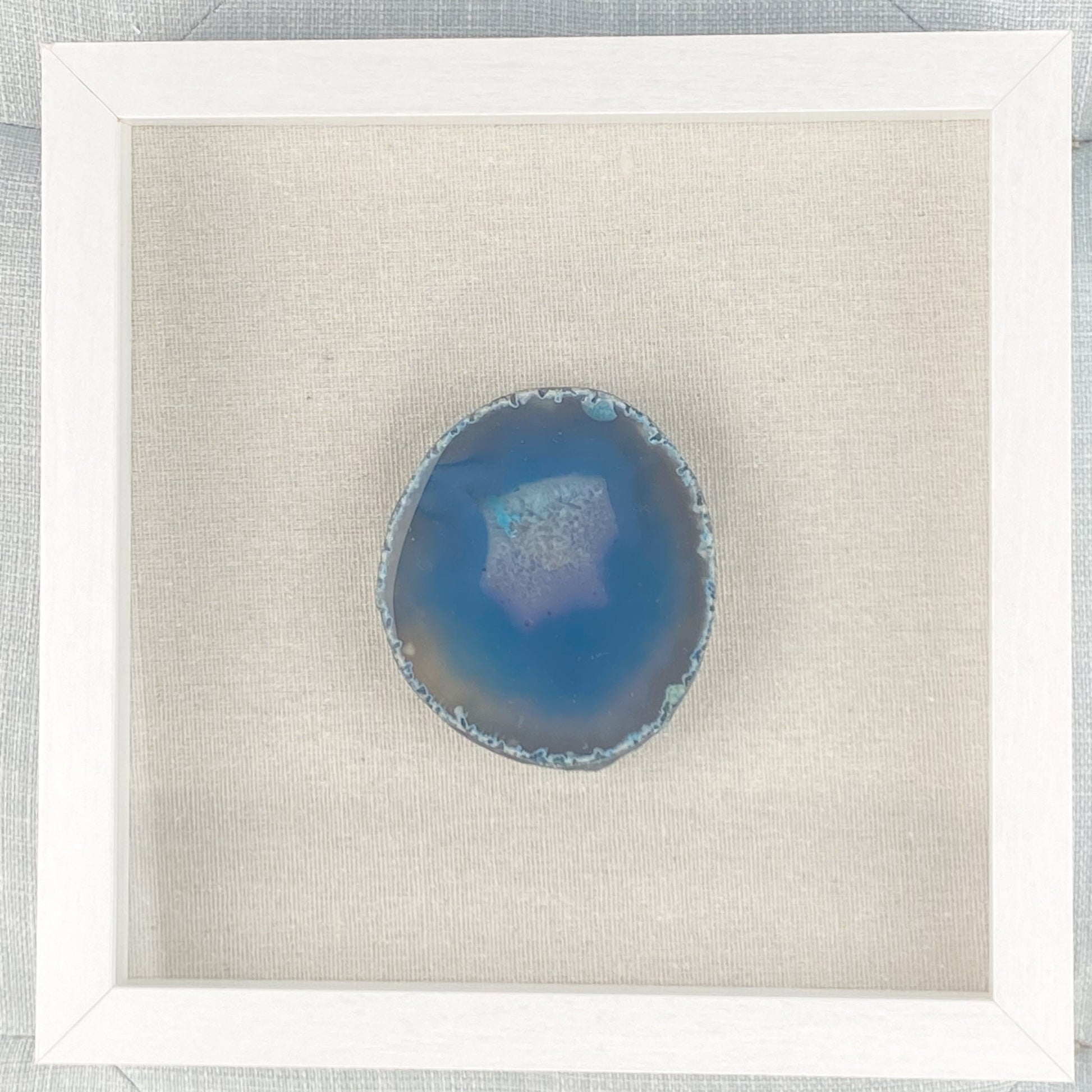 Blue agate stone in a white frame on a light gray background